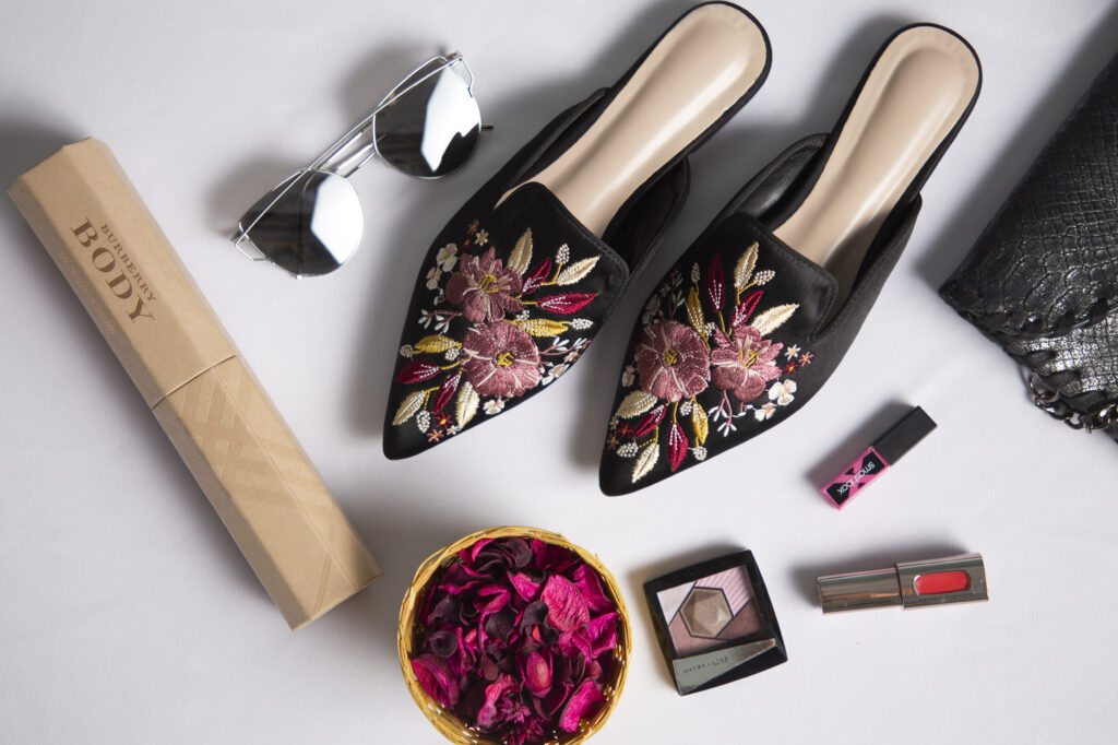 Pair of black women mules footwear with a flower woven design