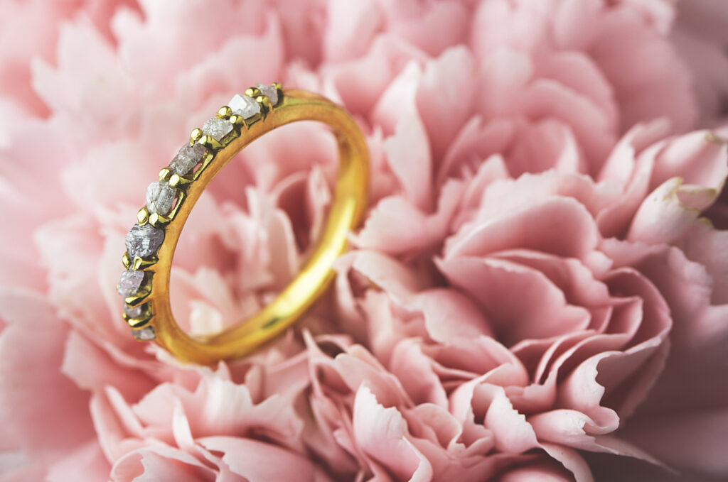 Finger ring made from gold and precious stones kept on a pink carnation flower